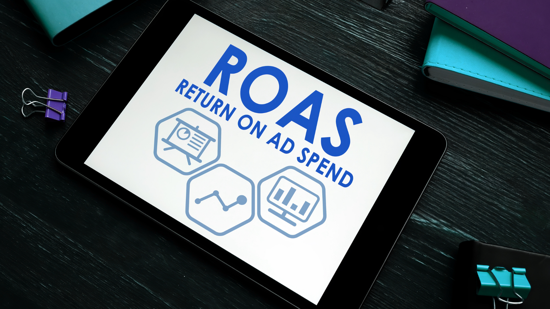 Pantalla de tablet mostrando el texto ROAS Return On Ad Spend con iconos de marketing y analítica